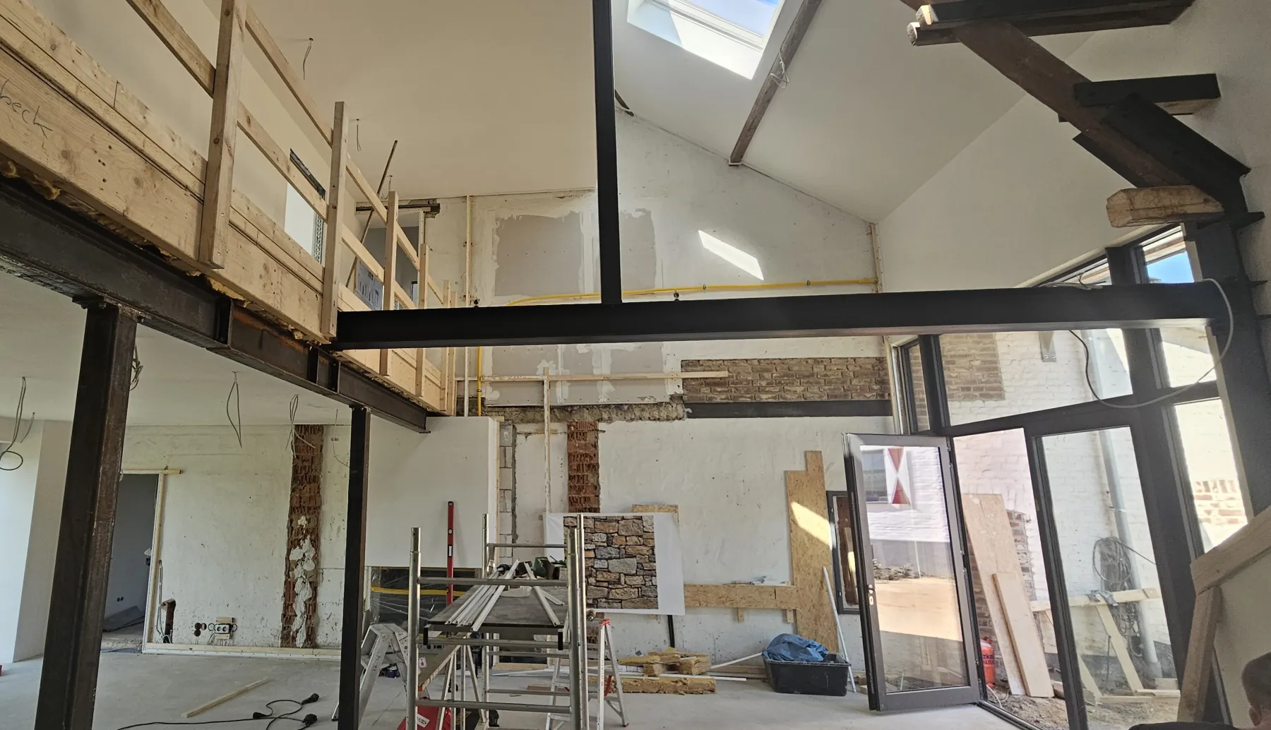 Wohnloft im Rohbau mit Stahlträgern und offener Decke vor Montage der bedruckten Akustikwand — Annotec-Projekt